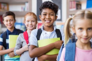 A group of schoolchildren smiling and standing in a line.