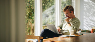 This image shows a man looking at his laptop.