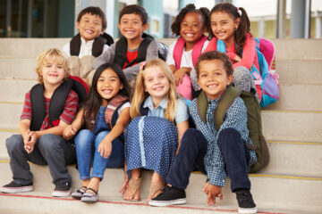 Elementary-aged students pose together on their school’s front steps.