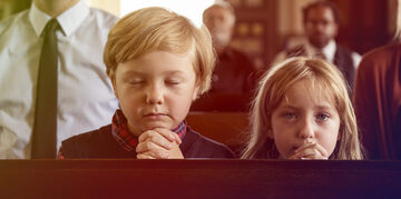 Two children praying in church.