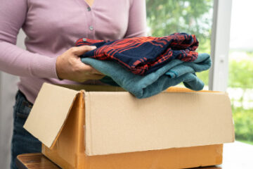 A woman putting clothing into a cardboard box for a clothing fundraiser.