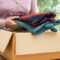 A woman putting clothing into a cardboard box for a clothing fundraiser.